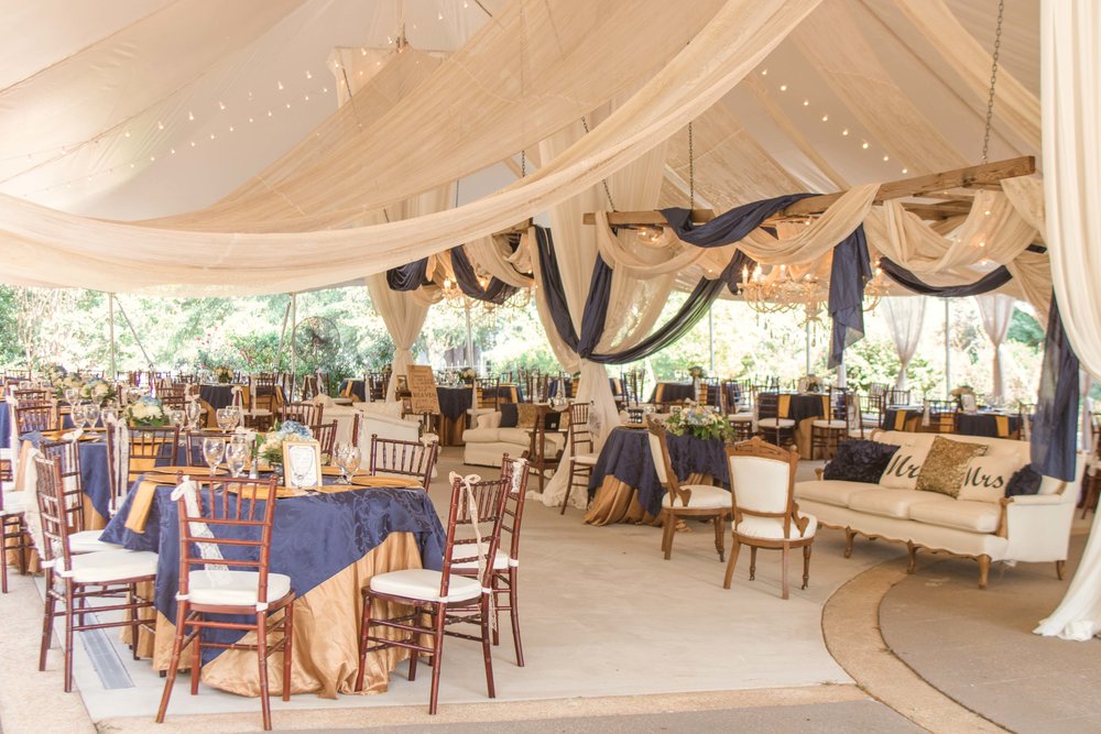 wedding reception tent at the gassaway mansion. The table coverings are navy and gold and there is stunning drapery everywhere in cream and navy.