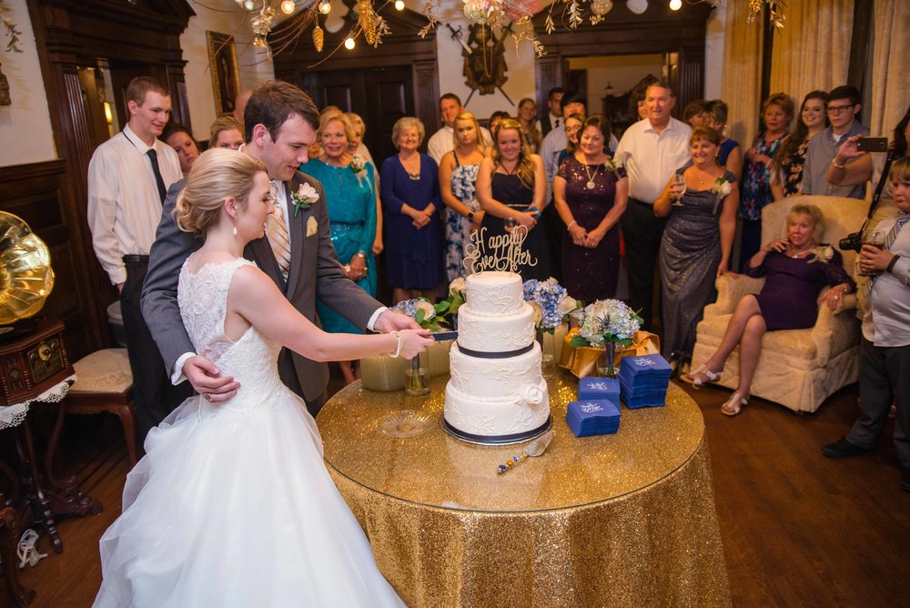 cake cutting at the gassaway mansion. the bride and groom are cutting the cake with the guests behind them.