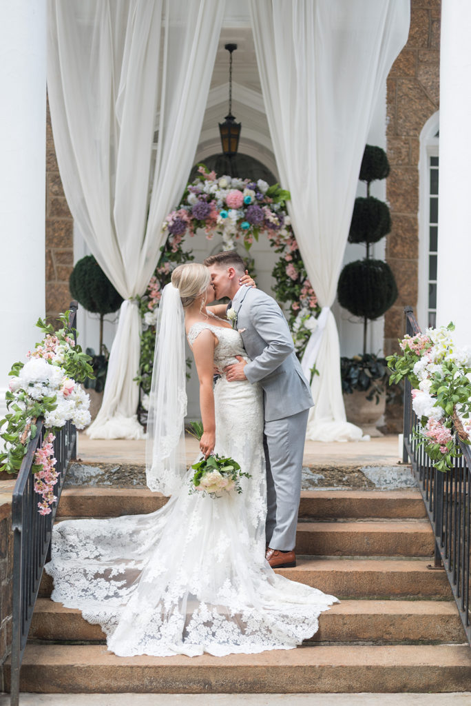 wedding portraits on the steps of the gassaway mansion. The couple is embracing, kissing, and the groom is dipping the bride back romantically.