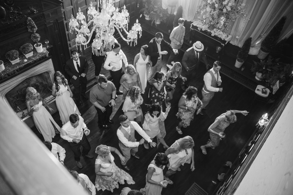 dancing at the gassaway mansion. The image is taken from the balcony looking below on the wedding guests dancing. the image is in black and white.