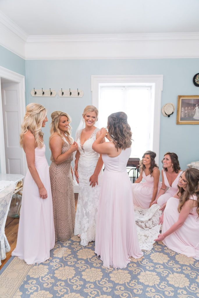 Bridesmaids Getting Ready in the Bride's Room at the Gassaway Mansion. The bridesmaids are helping the bride with her dress and they are wearing blush dresses