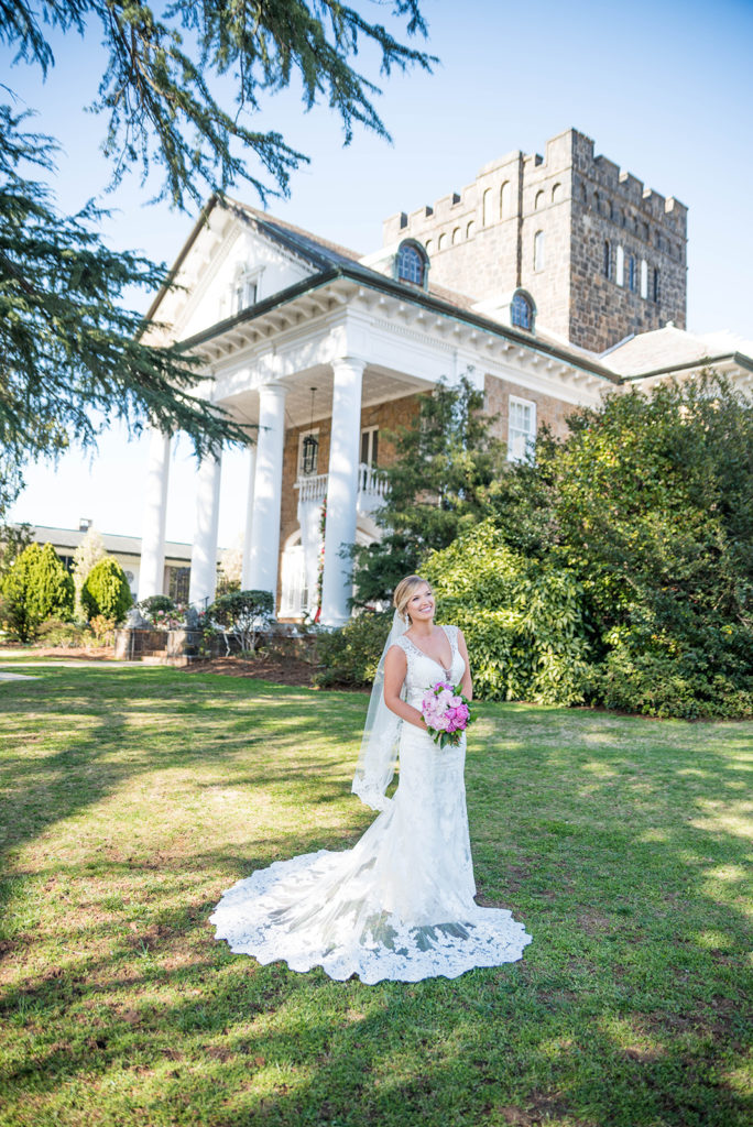 Bridal portrait of a bride in front of the gassaway mansion. You can see the castle-esque tower of the mansion in the background. It's summertime and the greenery is vibrant.