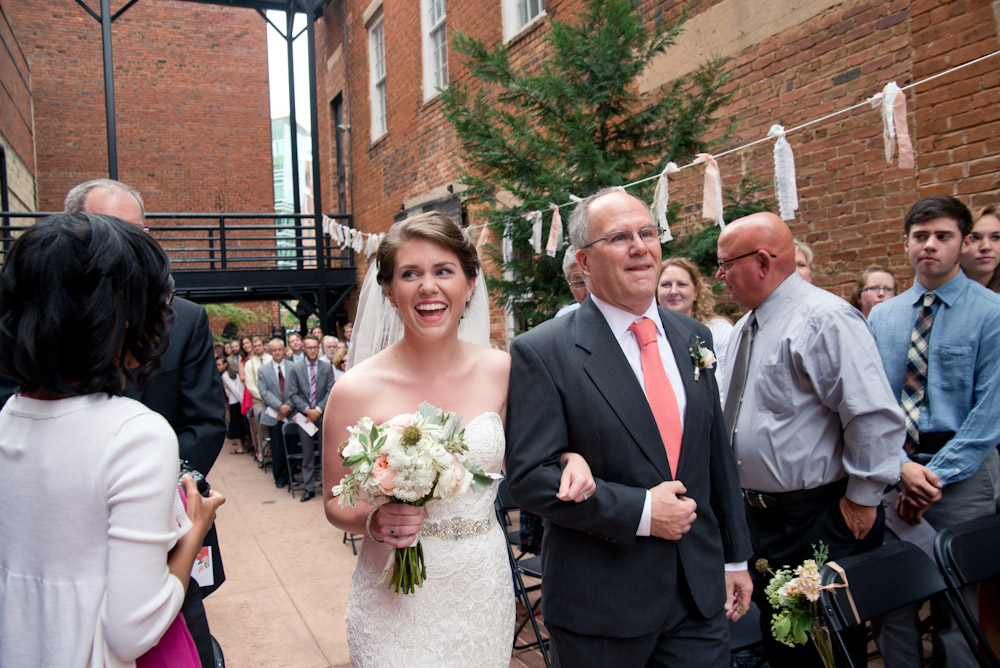 A bride walks down the aisle with her father during the processional at Larkins on the River