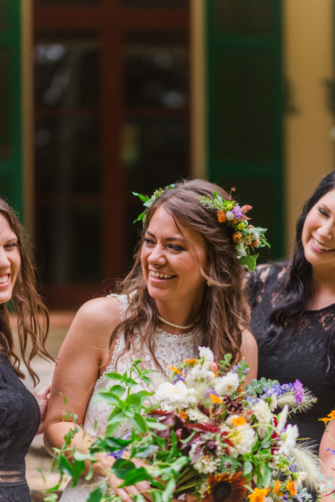 Iron Oak Barn Wedding in Pendleton SC - A bride wearing a flower crown and holding a bouquet smiles at her bridesmaids