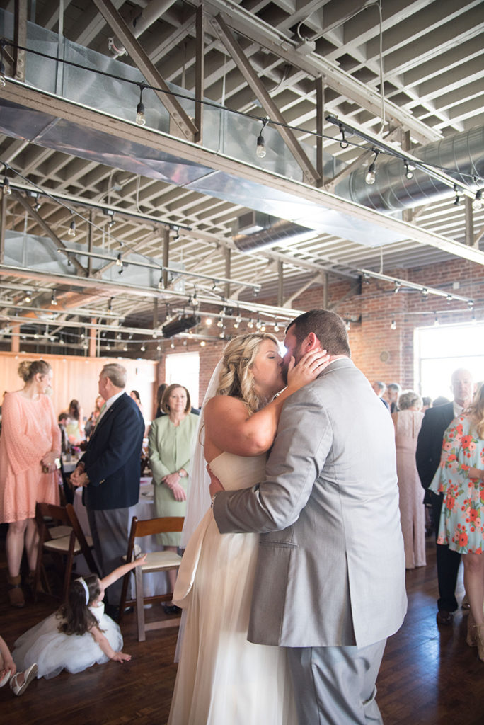A bride and groom share a kiss at a wedding reception at The Upper Room in Greenville, SC
