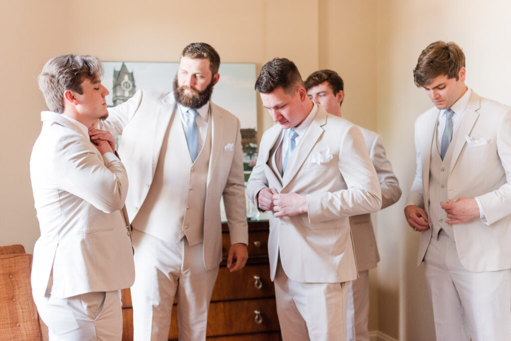 Groomsmen getting ready by straightening their ties and buttoning their jackets at The Bleckley Inn in Anderson, SC