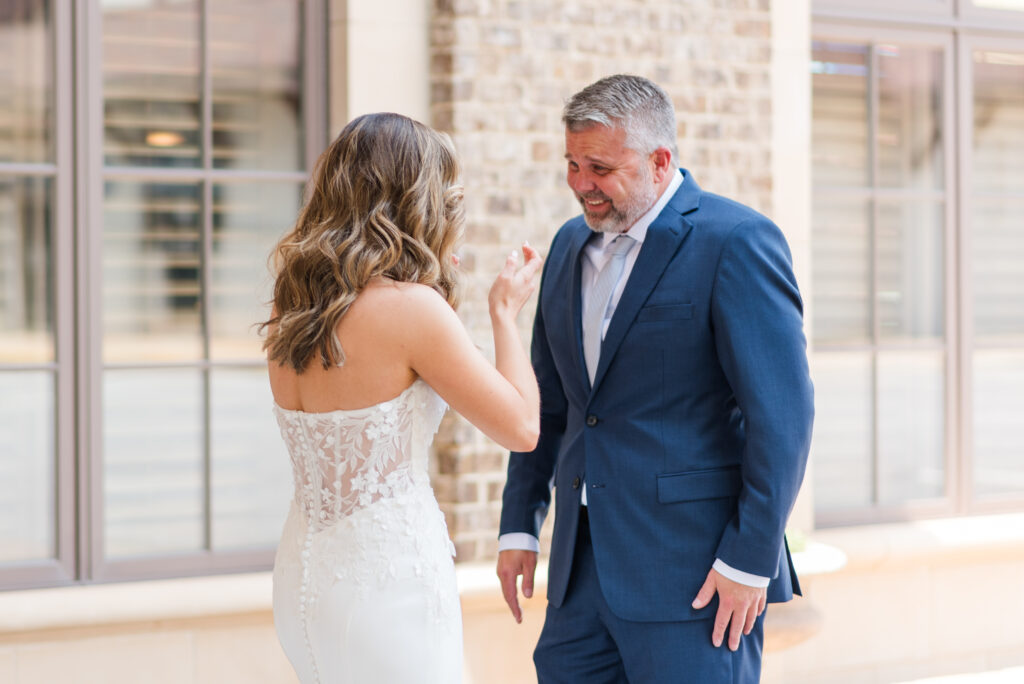 A bride's father smiles at her excitedly during their first look at the bleckley inn