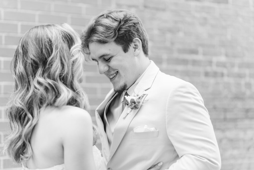 A groom smiles at his bride during their first look in the courtyard of the bleckley inn